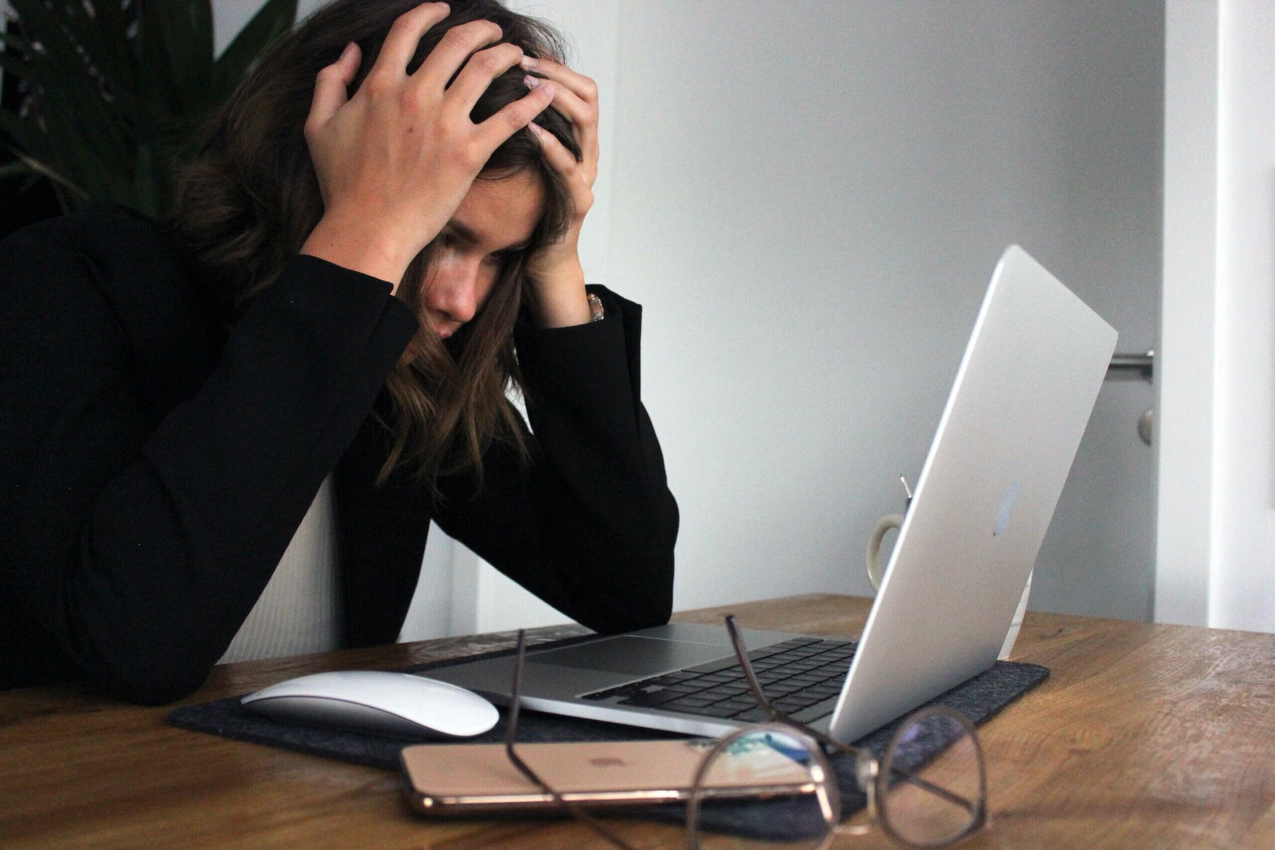 Woman looking at her laptop, appearing to be frustrated